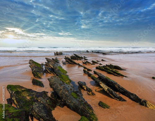 Rock formations on sandy beach and blue sky with cumulus clouds (Algarve, Costa Vicentina, Portugal).