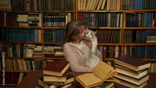 Obraz na plátně Woman with a cat in the library.