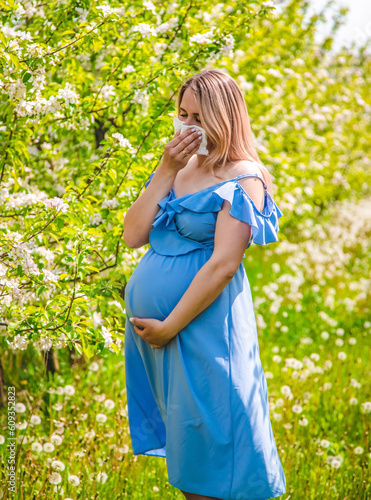 A pregnant woman in the garden of flowering apple trees is allergic. Selective focus.