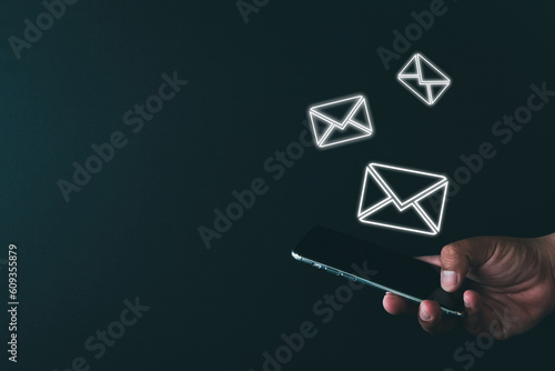 New message notification,Business Email concept.,Hand holding smartphone with envelope icon on black background with copyspace use for technology idea.