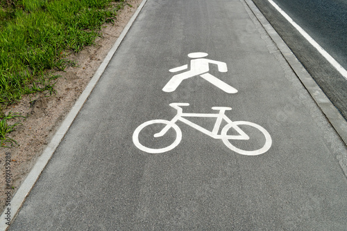Сombined road sign of bicycle and pedestrian lane on the asphalt sidewalk. Close-up symbol on a straight pavement.