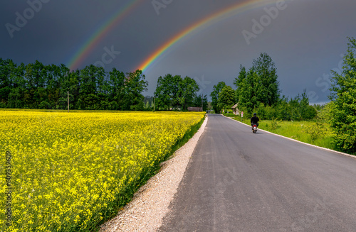 Countryside and agricultural landscape with rainbow over the road and field o...