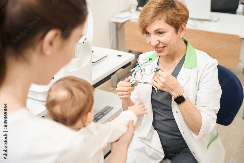 Fototapeta premium Pediatric ophthalmologist showing ophthalmic device to child