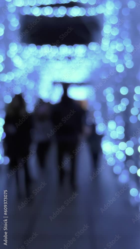 Festive atmosphere, decorated passage, defocused people walking, slow motion, vertical footage Festive atmosphere, decorated passage, defocused people walking, slow motion, vertical footage