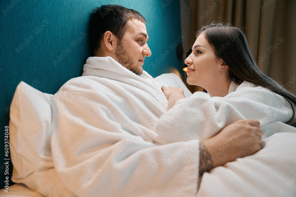 Couple in bathrobes look at each other lovingly Couple in bathrobes look at each other lovingly