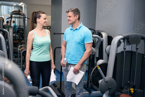 Smiling sporty lady talking to her fitness partner before workout