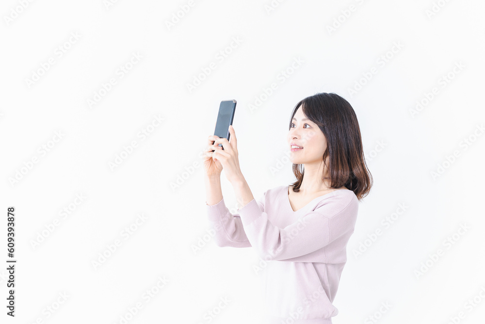 笑顔でスマホ撮影をする若い女性