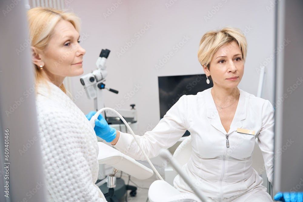 Photo of female gynecologist who conducts breast examination using ultrasound Photo of female gynecologist who conducts breast examination using ultrasound
