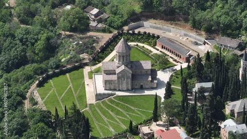 Aerial view of monastic complex of Bodbe nunnery on hillside among tall Cypress trees with Church of St. Nino on sunny day, Sighnaghi, Georgia photo