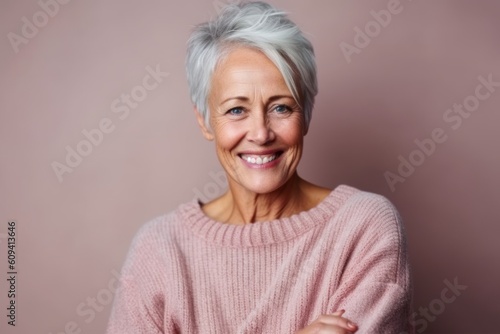 Portrait of a smiling senior woman with grey hair on a pink background