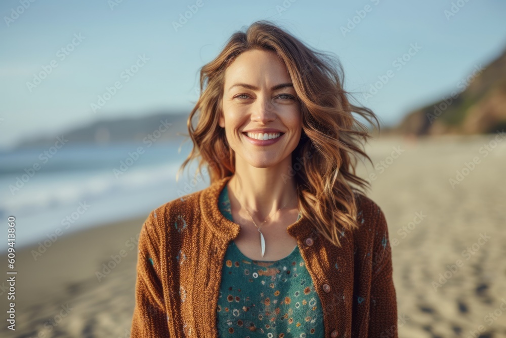 Portrait of smiling woman standing on beach and looking at camera.