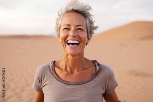 Portrait of happy senior woman laughing in the middle of the desert