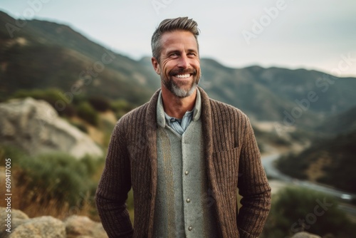 Portrait of smiling man looking at camera while standing on mountain road