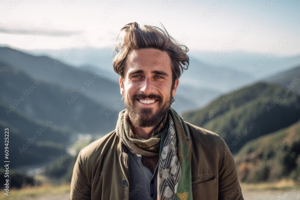 Portrait of a handsome young man standing in the mountains and smiling