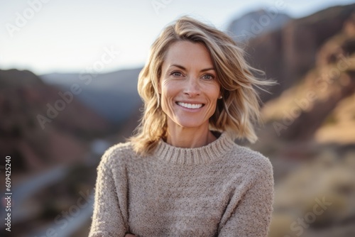 Medium shot portrait photography of a grinning woman in her 40s that is wearing a cozy sweater against a beautiful and breathtaking mountain vista background . Generative AI