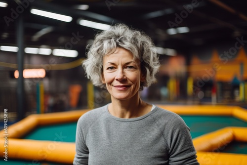 Portrait of smiling senior woman standing on a trampoline indoors