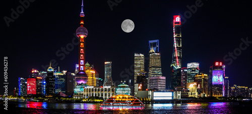 Night view of Shanghai under full moon with tour boat on Huangpu River and the three towers, Oriental Pearl Tower, Shanghai Tower, Shanghai World Financial Center photo