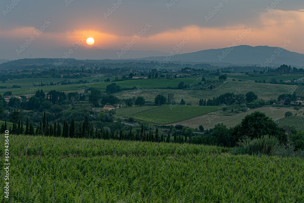 Setting sun breaks through clouds over vineyards in Tuscany region of Italy.