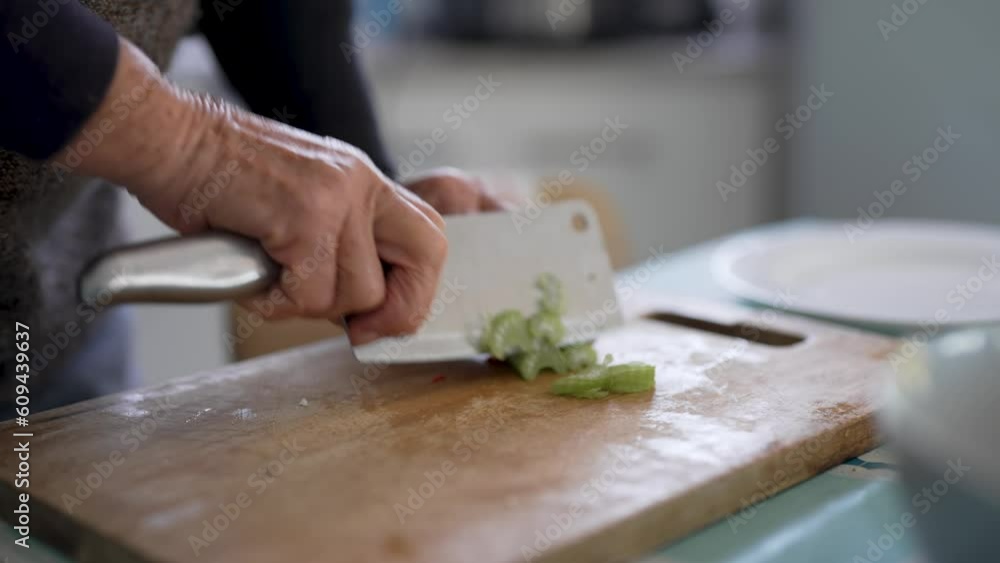 view of senior woman hands cutting celery on a wooden board in her home kitchen view of senior woman hands cutting celery on a wooden board in her home kitchen