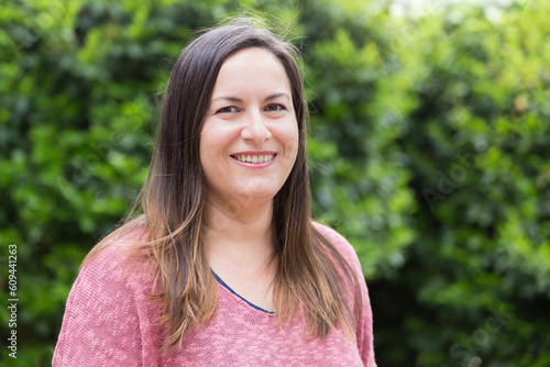 Portrait of a beautiful 40-45 years old woman posing in the park on a sunny day. Confidence and tranquility of a mature woman. Happiness, lifestyle.