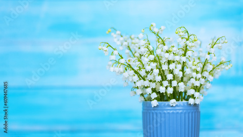 a bouquet of spring lilies of the valley in a blue vase on a blue background. bouquet of lilies of the valley close-up. background with lilies of the valley.