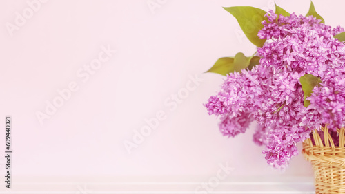 a bouquet of lilacs in a basket on a pink background. a postcard with a bouquet of lilacs. background with lilac flowers.