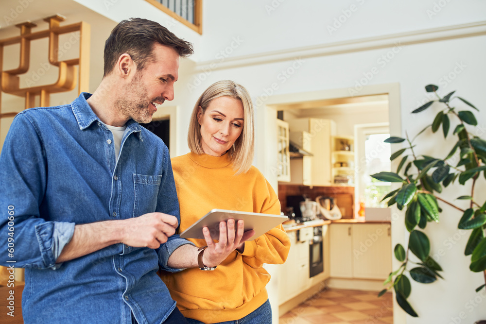 © baranq - Mid adult couple at home planning new interior design with digital tablet
