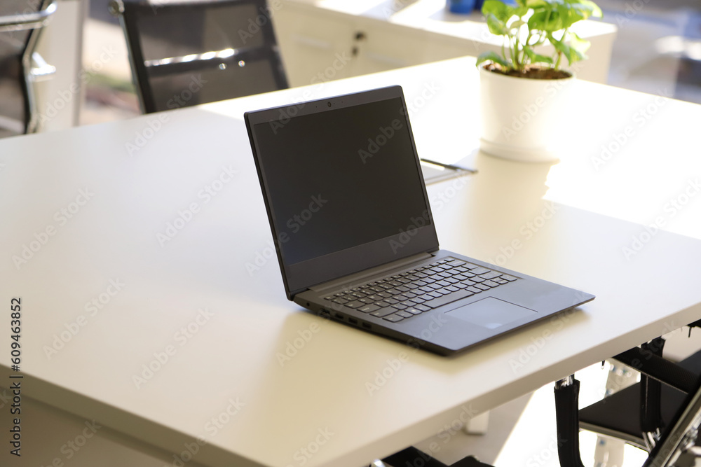 Fototapeta premium Laptop on desk with empty screen and copy space in an office. Laptop screen mockup.
