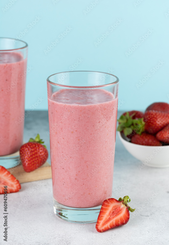 Strawberry smoothie or milkshake with berries on a blue background. Summer beverages. Strawberry smoothie or milkshake with berries on a blue background. Summer beverages.