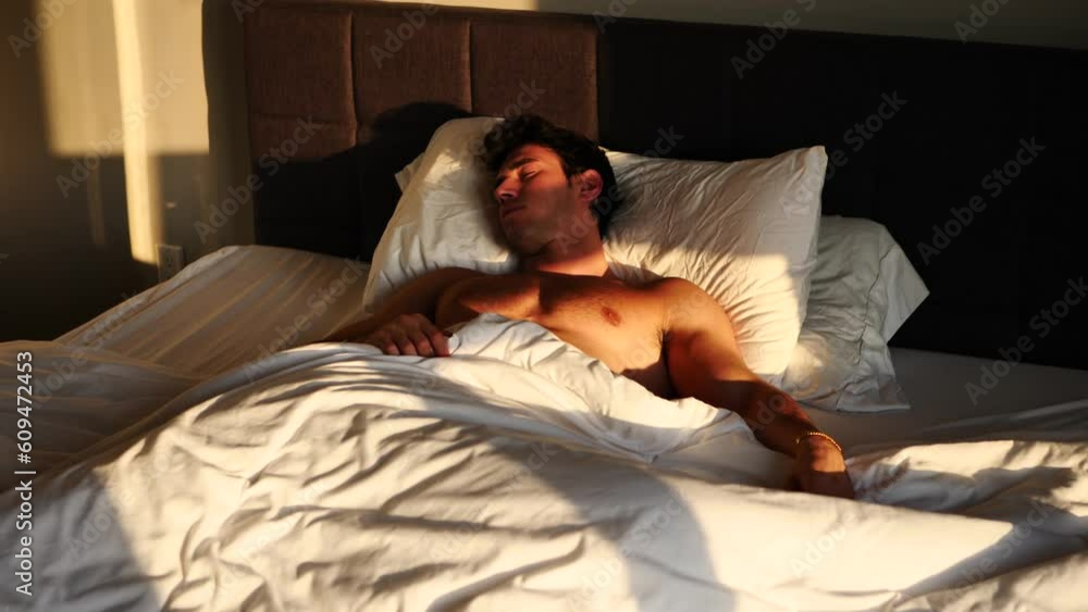 Handsome shirtless young man in bed sleeping and waking up vídeo de Stock Adobe Stock