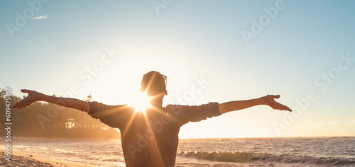Young female feeling grateful, joyful standing outdoors in the sunrise	