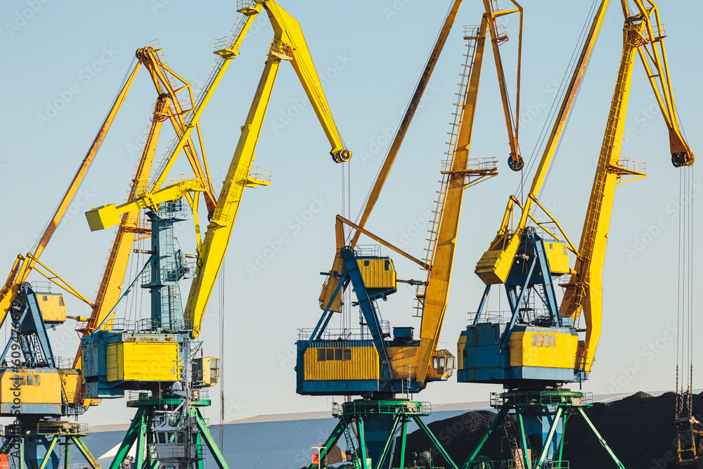 Larger cranes in the port, cranes load bulk materials. The work of cranes in the seaport Larger cranes in the port, cranes load bulk materials. The work of cranes in the seaport