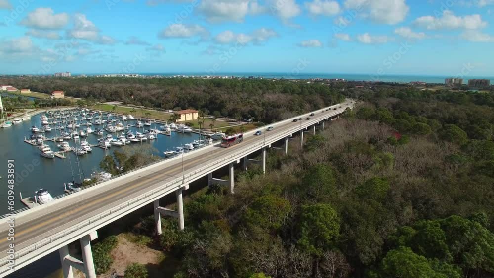 Aerial Shot Of Vehicles On Bridge Over Sea Near Harbor, Drone Flying Backward Over Trees Against Sky - Daytona Beach, Florida Aerial Shot Of Vehicles On Bridge Over Sea Near Harbor, Drone Flying Backward Over Trees Against Sky - Daytona Beach, Florida