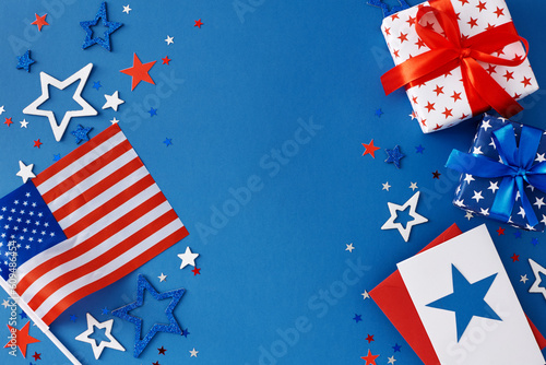 Idea for a Fourth of July party. Top view flat lay of american flag, gift boxes, postcard, stars in national colors on blue background with blank space for text or promotion