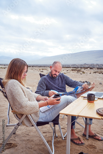 mid adult caucasian adventurous couple sitting outdoors looking at map with Atacama desert landscape background