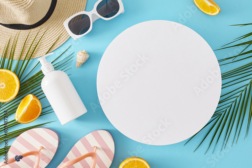Sunscreen cosmetics concept during the summertime. Top view flat lay of cosmetic bottle, beach accessories, oranges, palm leaves, seashell on pastel blue background with blank circle for advert