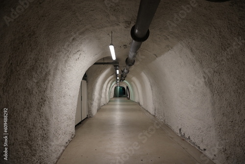 Underground passage made from concrete with lights and pipe on the ceiling entrance or exit from the bunker, shelter, mine
