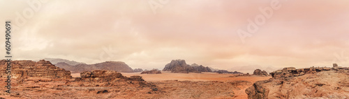 Red orange Mars like landscape in Jordan Wadi Rum desert  mountains background overcast morning  wide panorama. This location was used as set for many science fiction movies