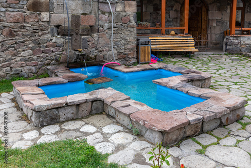 Cross-shaped stone pool with turquoise clear water in Zarzma Monastery of Transfiguration, medieval Orthodox Christian monastery located in the village of Zarzma, Georgia. © Cleop6atra