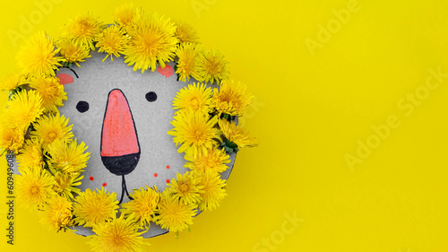 close-up of a lion's head made of cardboard and dandelions on yellow background. children's crafts
