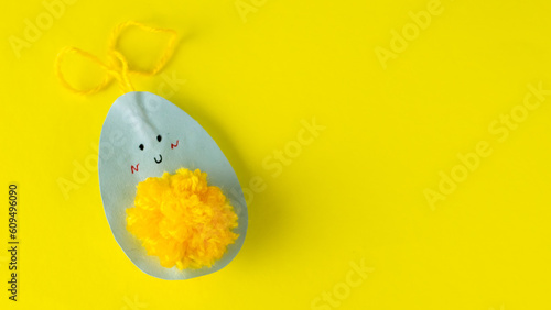 yellow easter egg  made of paper and threads on yellow background. children's crafts