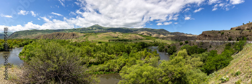 Mtkvari river valley panorama in Samtskhe Javakheti region in Southern Georgia with lush green vegetation and Lesser Caucasus mountains in the background.