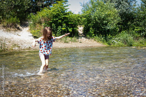 Obraz na plátně Caucasian child girl wading a clear stream on a bright sunny day