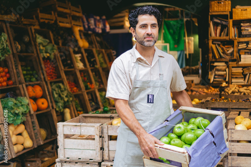 middle-aged Latino man, greengrocer in his organic shop with green apples in his hands