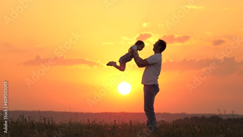 dad plays with his little daughter, joyfully throws the child into the sky. happy family in nature. dad and child. family resting at sunset in the field. happy healthy family walking in the fresh air.