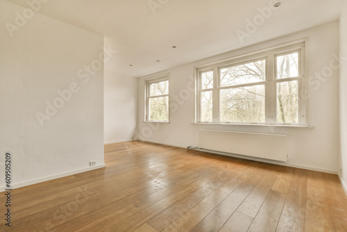an empty room with wood flooring and large windows looking out to the trees outside in the room is white