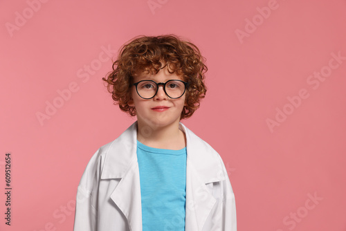 Portrait of little boy in medical uniform and glasses on pink background