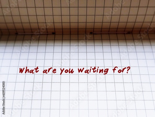 Notebook on red background with pen writing What are you waiting for? - to tell someone or self reminder to do something immediately,  to hurry up and do it now photo