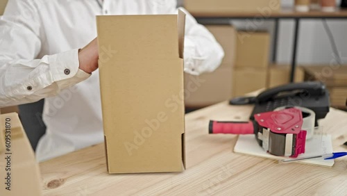 Young caucasian man ecommerce business worker packing cardbord box at office photo