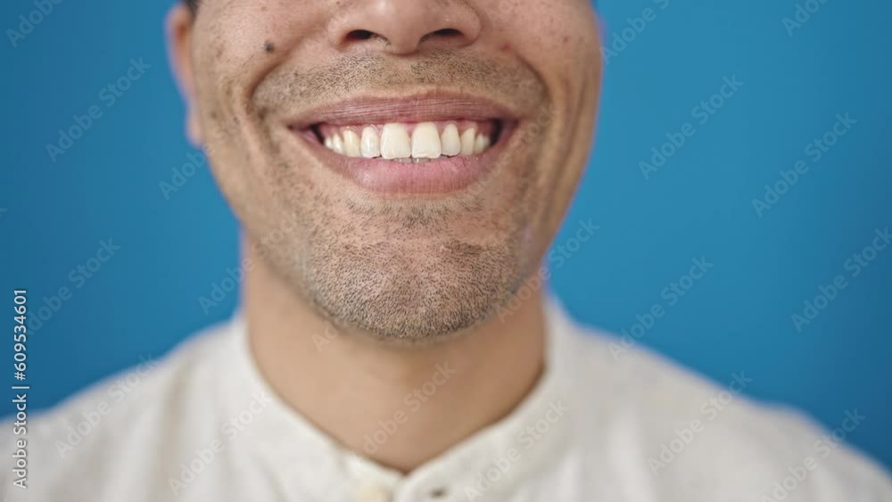 Young hispanic man close up of smile over isolated blue background Young hispanic man close up of smile over isolated blue background